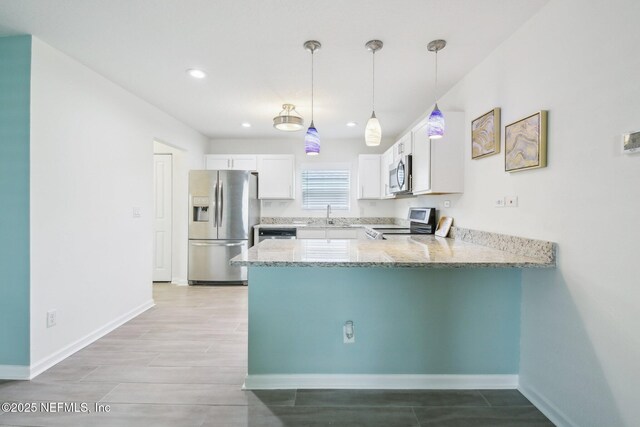 451 Sawmill Landing Dr, Saint Augustine, FL 32086 - kitchen with stainless steel appliances, a peninsula, light stone countertops, a sink, and white cabinetry