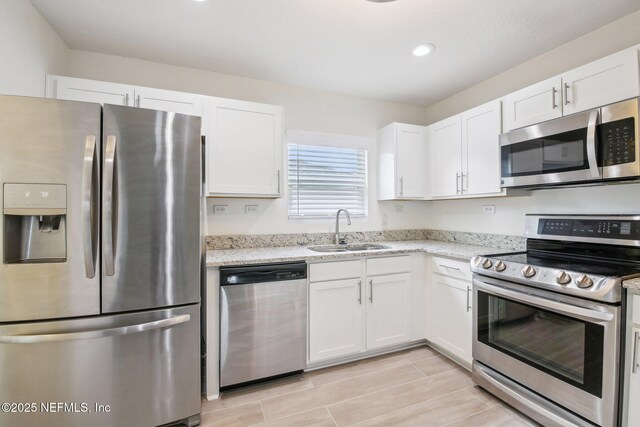 451 Sawmill Landing Dr, Saint Augustine, FL 32086 - kitchen featuring stainless steel appliances, a sink, white cabinets, light stone counters, and recessed lighting