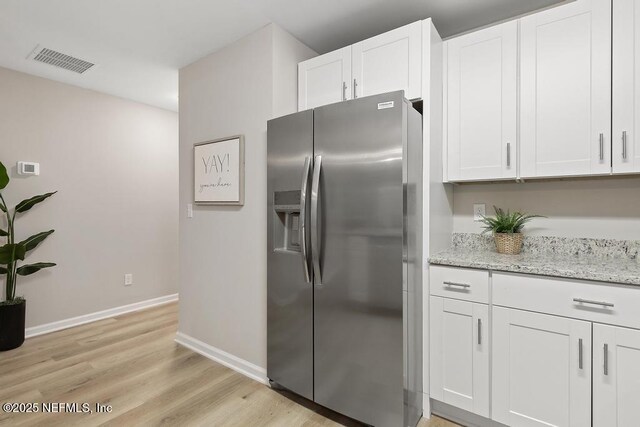 889 Aiken St, Saint Augustine, FL 32084 - kitchen featuring stainless steel refrigerator with ice dispenser, white cabinets, light wood-style flooring, and light stone counters