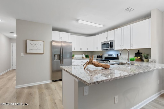 889 Aiken St, Saint Augustine, FL 32084 - kitchen featuring appliances with stainless steel finishes, light wood-style flooring, a peninsula, light stone counters, and recessed lighting