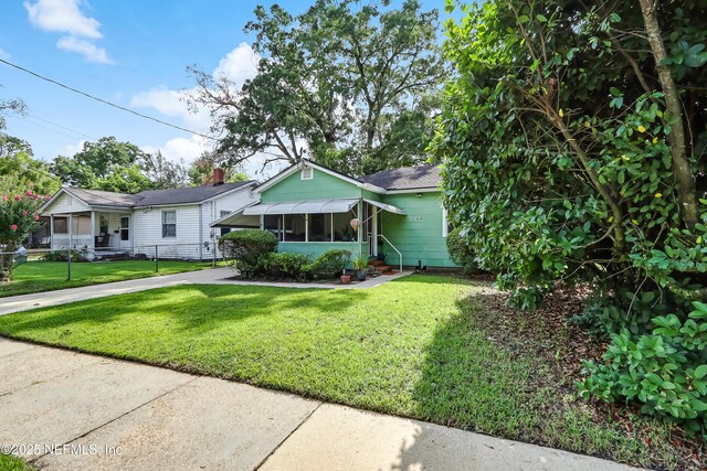 1131 Wycoff Ave, Jacksonville, FL 32205 - single story home featuring a front lawn, a sunroom, driveway, and a shingled roof