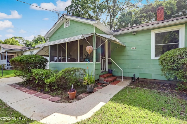 1131 Wycoff Ave, Jacksonville, FL 32205 - view of front of home featuring entry steps, a chimney, a front yard, and a sunroom