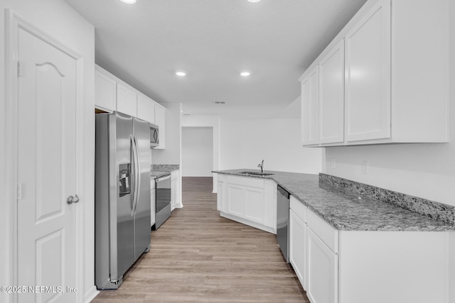 37132 Whippoorwill Ct, Hilliard, FL 32046 - kitchen featuring appliances with stainless steel finishes, white cabinets, recessed lighting, light wood-style flooring, and a sink
