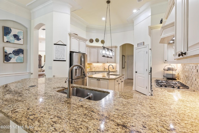 2435 Den St, Saint Augustine, FL 32092 - kitchen with arched walkways, appliances with stainless steel finishes, a sink, light stone counters, and crown molding
