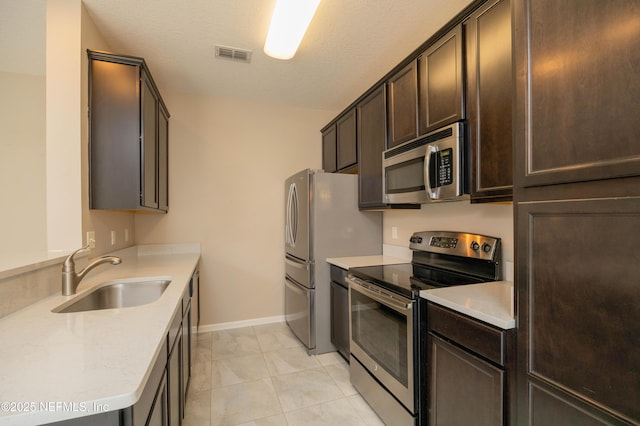 246 Moultrie Village Ln, Saint Augustine, FL 32086 - kitchen featuring stainless steel appliances, a sink, dark brown cabinets, light countertops, and baseboards