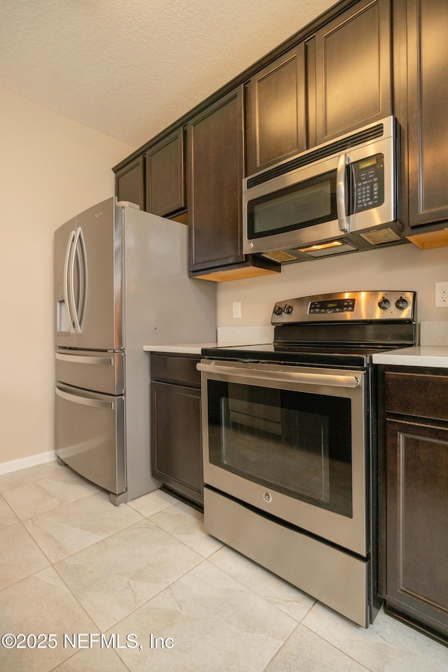 246 Moultrie Village Ln, Saint Augustine, FL 32086 - kitchen featuring appliances with stainless steel finishes, dark brown cabinetry, light countertops, and baseboards