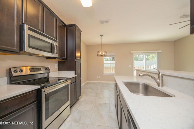 246 Moultrie Village Ln, Saint Augustine, FL 32086 - kitchen featuring stainless steel appliances, a sink, dark brown cabinets, hanging light fixtures, and light stone counters