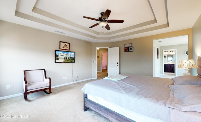 12237 Woodview Dr, Jacksonville, FL 32246 - bedroom with a tray ceiling, light carpet, baseboards, connected bathroom, and a ceiling fan