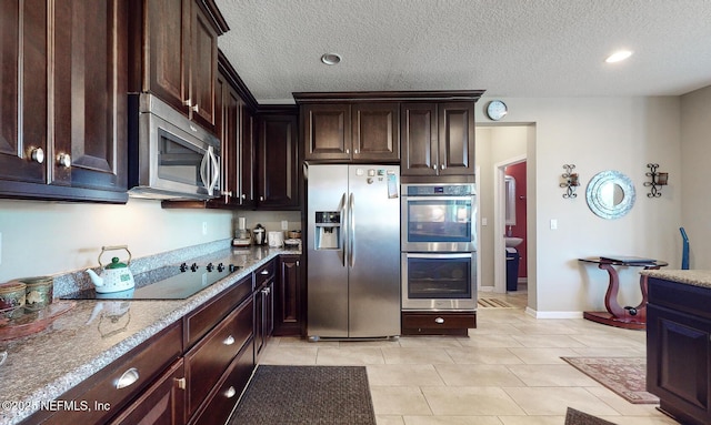 12237 Woodview Dr, Jacksonville, FL 32246 - kitchen with appliances with stainless steel finishes, light tile patterned floors, dark brown cabinets, light stone countertops, and a textured ceiling