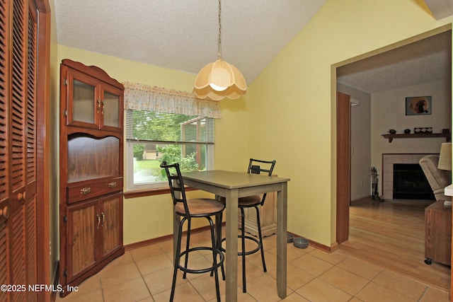 426 Harvest Bend Dr, Fleming Island, FL 32003 - dining room featuring light tile patterned floors, a fireplace, a textured ceiling, vaulted ceiling, and baseboards