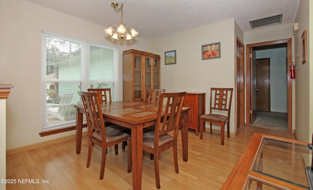 426 Harvest Bend Dr, Fleming Island, FL 32003 - dining area featuring a chandelier, light wood-type flooring, a textured ceiling, and baseboards