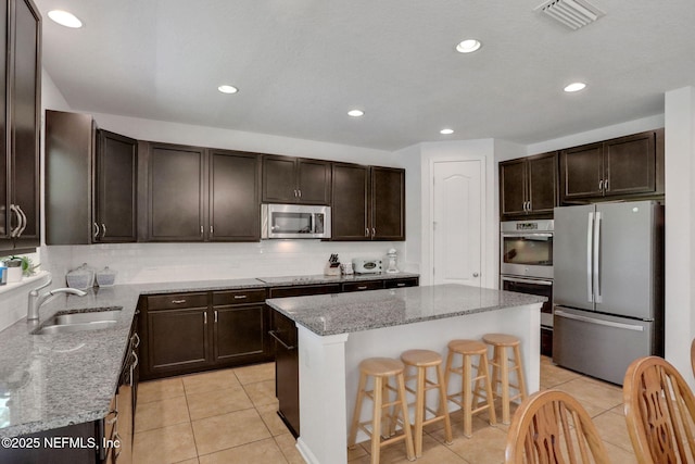 1090 Wetland Ridge Cir, Middleburg, FL 32068 - kitchen featuring stainless steel appliances, a center island, a sink, dark brown cabinetry, and recessed lighting