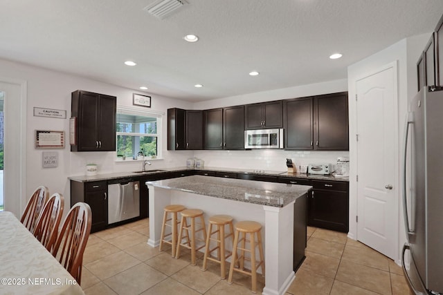 1090 Wetland Ridge Cir, Middleburg, FL 32068 - kitchen featuring appliances with stainless steel finishes, a kitchen island, decorative backsplash, light tile patterned floors, and recessed lighting