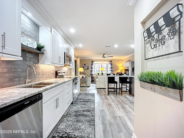 5375 Ortega Farms Blvd Unit 1011, Jacksonville, FL 32210 - kitchen with stainless steel appliances, a sink, light wood finished floors, ceiling fan, and tasteful backsplash
