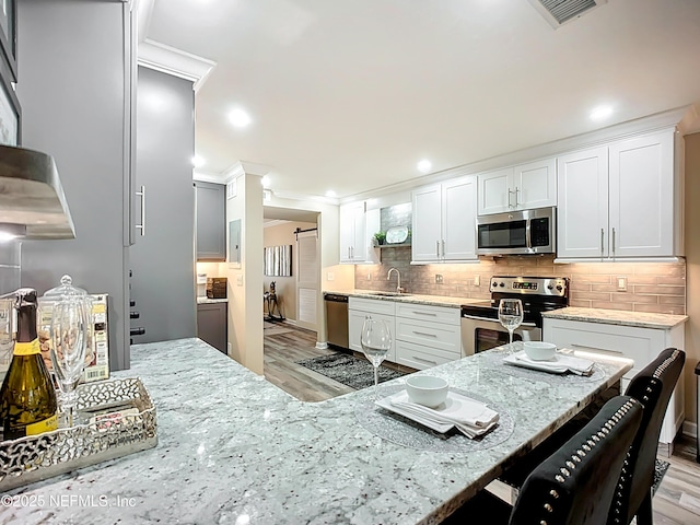 5375 Ortega Farms Blvd Unit 1011, Jacksonville, FL 32210 - kitchen with stainless steel appliances, light wood finished floors, ornamental molding, light stone countertops, and a breakfast bar area