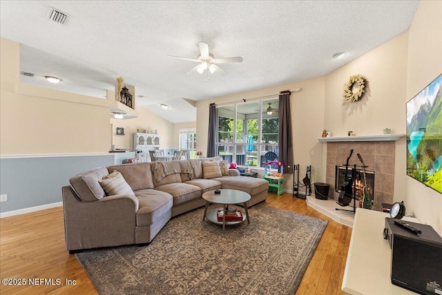3910 Selig Ct, Middleburg, FL 32068 - living area with ceiling fan, a textured ceiling, wood finished floors, a tile fireplace, and vaulted ceiling