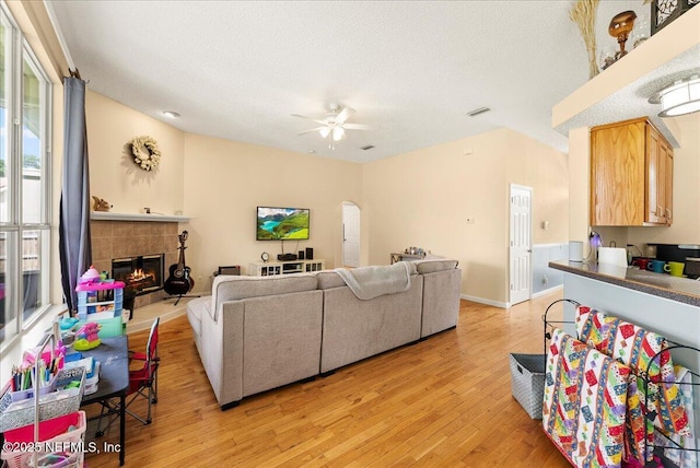 3910 Selig Ct, Middleburg, FL 32068 - living area with light wood-style floors, a ceiling fan, a fireplace, a textured ceiling, and arched walkways