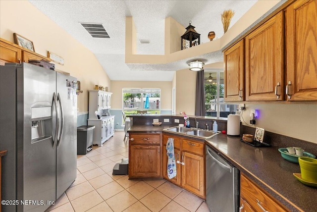 3910 Selig Ct, Middleburg, FL 32068 - kitchen with appliances with stainless steel finishes, a sink, brown cabinetry, vaulted ceiling, and a textured ceiling