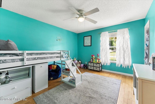 3910 Selig Ct, Middleburg, FL 32068 - bedroom featuring wood finished floors, a textured ceiling, a ceiling fan, and baseboards