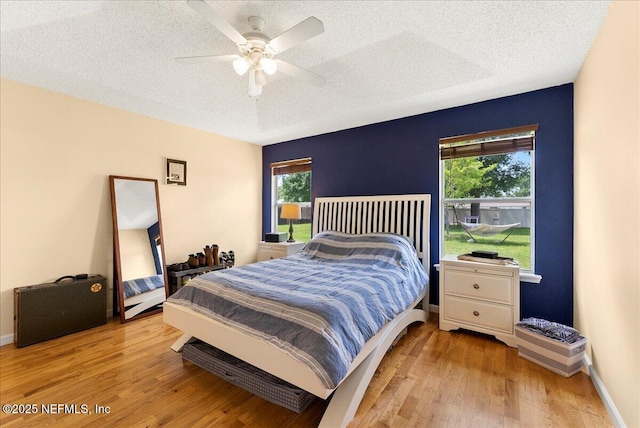 3910 Selig Ct, Middleburg, FL 32068 - bedroom featuring a textured ceiling, light wood-style floors, multiple windows, a ceiling fan, and baseboards