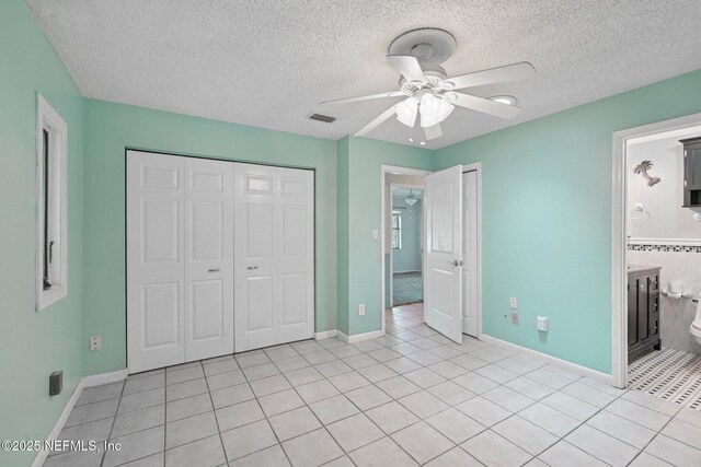 9620 Baylor Ave, Hastings, FL 32145 - unfurnished bedroom with light tile patterned floors, a textured ceiling, a closet, baseboards, and a ceiling fan