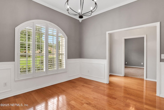 880 Buckeye Ln W, Saint Johns, FL 32259 - empty room featuring a chandelier, light wood-type flooring, crown molding, and wainscoting