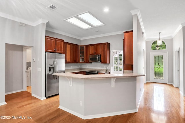 880 Buckeye Ln W, Saint Johns, FL 32259 - kitchen featuring appliances with stainless steel finishes, a peninsula, a kitchen breakfast bar, glass insert cabinets, and light wood-style floors