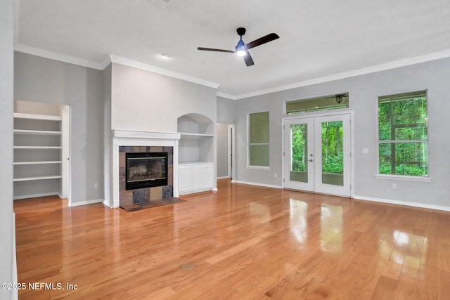 880 Buckeye Ln W, Saint Johns, FL 32259 - unfurnished living room featuring ceiling fan, a tile fireplace, built in features, light wood-type flooring, and crown molding