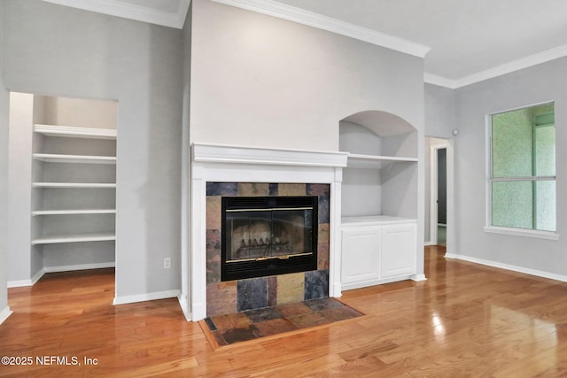 880 Buckeye Ln W, Saint Johns, FL 32259 - unfurnished living room with built in features, a tile fireplace, baseboards, wood finished floors, and ornamental molding