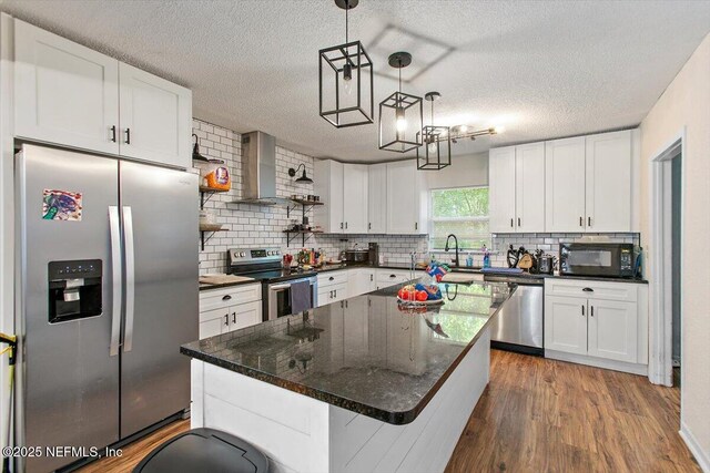 3020 Gilmore St, Jacksonville, FL 32205 - kitchen with stainless steel appliances, wall chimney exhaust hood, tasteful backsplash, white cabinets, and a textured ceiling