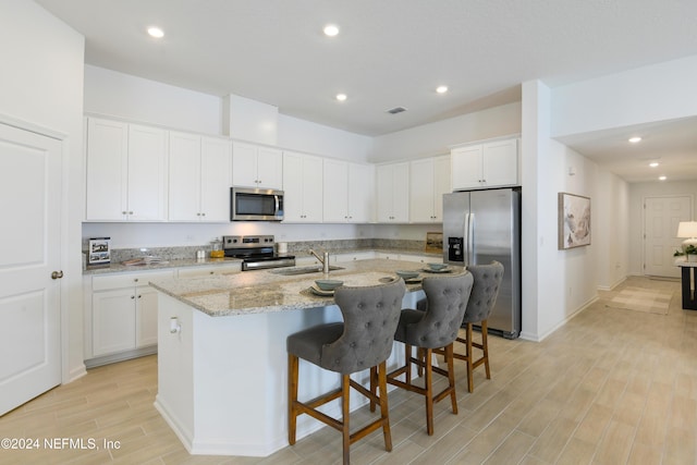 3369 Golden Eye Dr, Orange Park, FL 32065 - kitchen featuring appliances with stainless steel finishes, a sink, light wood-type flooring, a center island with sink, and white cabinetry