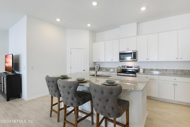 3369 Golden Eye Dr, Orange Park, FL 32065 - kitchen featuring appliances with stainless steel finishes, light wood-style floors, an island with sink, recessed lighting, and light stone countertops