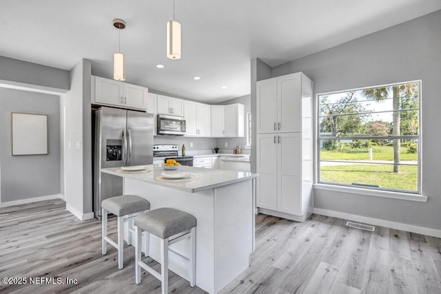 6903 Mayapple Rd, Jacksonville, FL 32211 - kitchen featuring appliances with stainless steel finishes, light countertops, white cabinetry, a center island, and light wood-type flooring