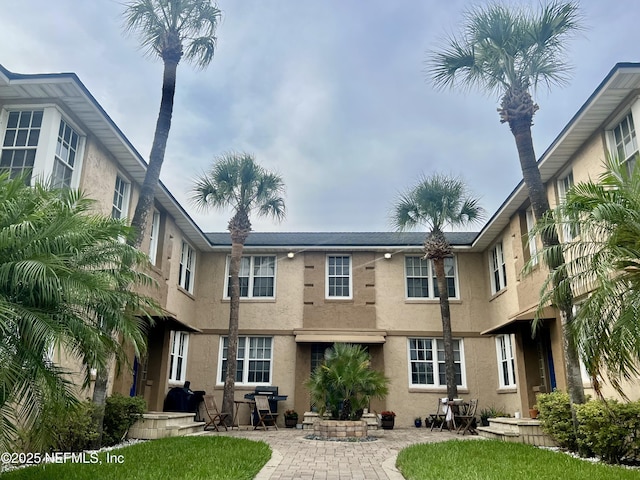 319 1st Ave N Unit 1-B, Jacksonville Beach, FL 32250 - rear view of house featuring stucco siding and a patio area