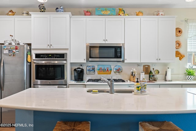 85464 Amaryllis Ct, Fernandina Beach, FL 32034 - kitchen with appliances with stainless steel finishes, white cabinetry, light stone countertops, and a kitchen bar