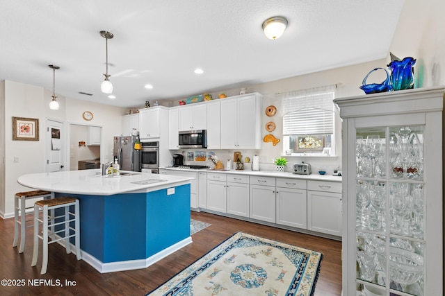 85464 Amaryllis Ct, Fernandina Beach, FL 32034 - kitchen with appliances with stainless steel finishes, white cabinetry, dark wood-style floors, an island with sink, and light countertops