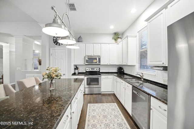 828 Lotus Ln N, Saint Johns, FL 32259 - kitchen with stainless steel appliances, a sink, dark wood-type flooring, white cabinetry, and pendant lighting