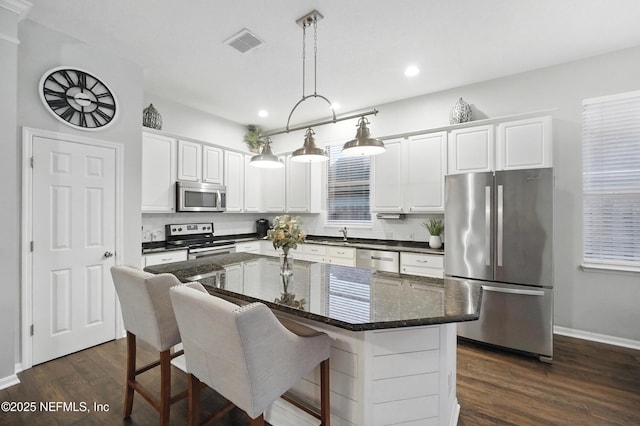 828 Lotus Ln N, Saint Johns, FL 32259 - kitchen featuring appliances with stainless steel finishes, dark wood-type flooring, recessed lighting, white cabinetry, and a center island