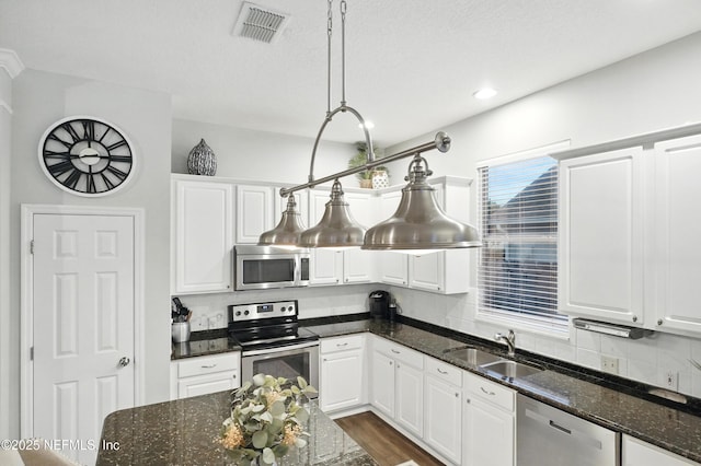 828 Lotus Ln N, Saint Johns, FL 32259 - kitchen featuring stainless steel appliances, a sink, white cabinets, dark stone counters, and recessed lighting