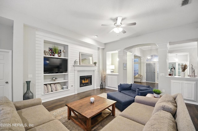 828 Lotus Ln N, Saint Johns, FL 32259 - living room featuring ornate columns, dark wood-style floors, arched walkways, a ceiling fan, and built in shelves