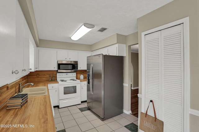 2650 Cardigan Ct, Orange Park, FL 32065 - kitchen with stainless steel appliances, a sink, white cabinetry, light tile patterned flooring, and wood counters
