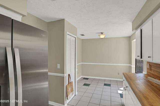 2650 Cardigan Ct, Orange Park, FL 32065 - kitchen with freestanding refrigerator, wood counters, light tile patterned floors, white cabinets, and a textured ceiling