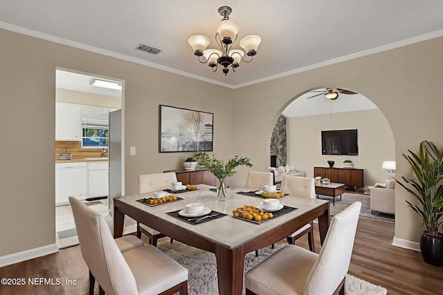 2650 Cardigan Ct, Orange Park, FL 32065 - dining room featuring arched walkways, dark wood-style floors, a chandelier, crown molding, and baseboards