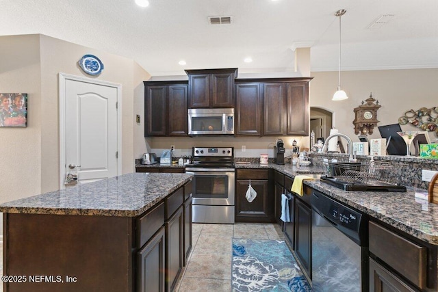 3912 Pipit Pt, Middleburg, FL 32068 - kitchen featuring appliances with stainless steel finishes, dark brown cabinetry, dark stone counters, arched walkways, and decorative light fixtures