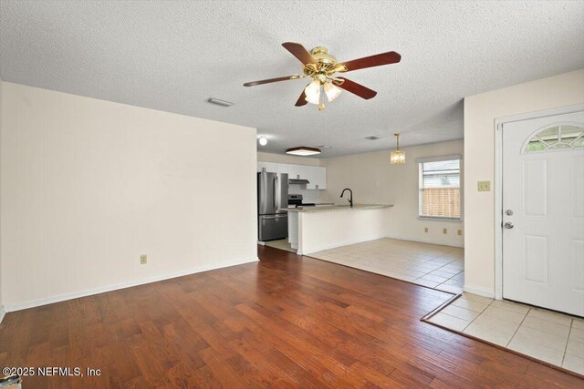 1528 Jordan St, Atlantic Beach, FL 32233 - unfurnished living room featuring wood finished floors, a ceiling fan, a sink, and a textured ceiling
