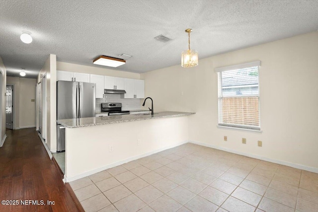 1528 Jordan St, Atlantic Beach, FL 32233 - kitchen featuring appliances with stainless steel finishes, under cabinet range hood, a peninsula, white cabinets, and light stone countertops