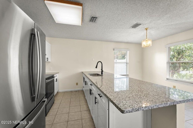 1528 Jordan St, Atlantic Beach, FL 32233 - kitchen with appliances with stainless steel finishes, a sink, white cabinetry, plenty of natural light, and a textured ceiling