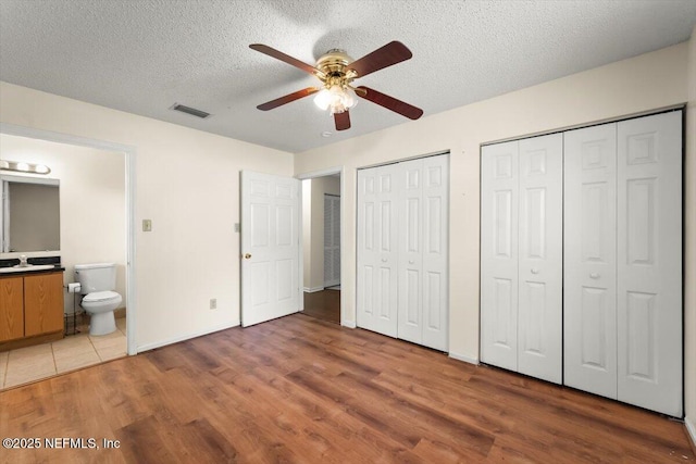 1528 Jordan St, Atlantic Beach, FL 32233 - unfurnished bedroom featuring multiple closets, wood finished floors, a textured ceiling, a sink, and connected bathroom
