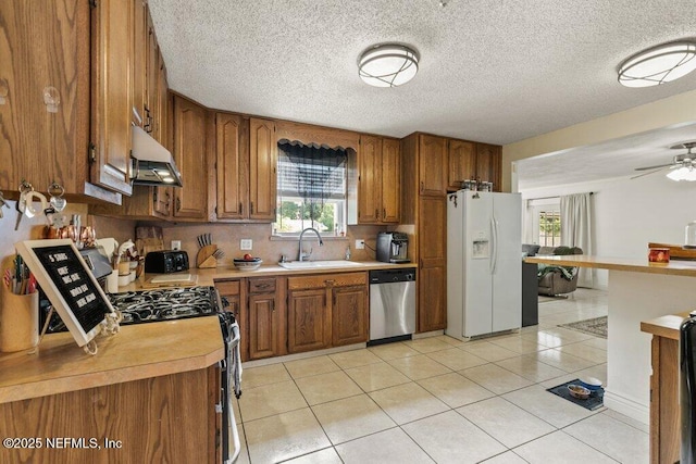 2041 Mill Creek Rd, Jacksonville, FL 32211 - kitchen featuring stainless steel dishwasher, white fridge with ice dispenser, a sink, under cabinet range hood, and brown cabinetry