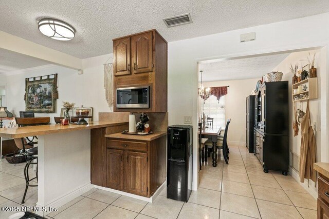 2041 Mill Creek Rd, Jacksonville, FL 32211 - kitchen featuring stainless steel microwave, a breakfast bar area, light tile patterned floors, a peninsula, and a chandelier